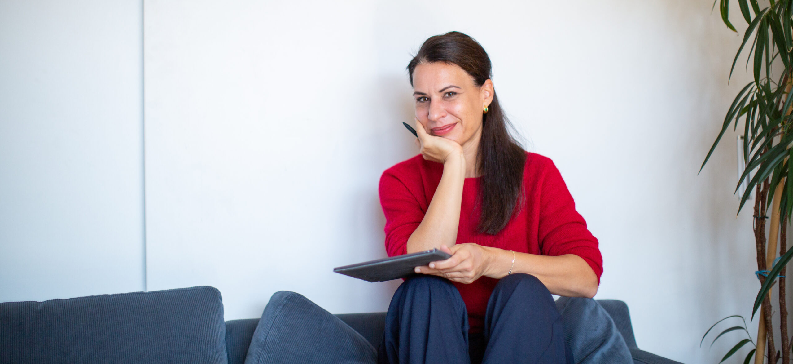 Lektorin Irene Steindl sitzt auf einem Sofa mit einem digitalen Notizbuch in der Hand.